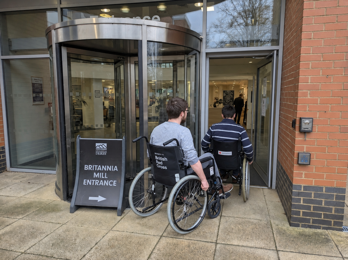 Students navigating a campus entrance using self-propelling wheelchairs